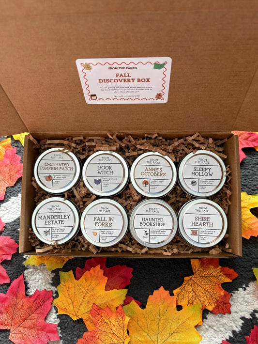An open brown cardboard gift box labeled 'Fall Discovery Box' filled with shredded paper and eight small round metal tins. The tins have white labels with autumn-themed names including 'Manderley Estate', 'Book Witch', 'Slee
py Hollow', and others.