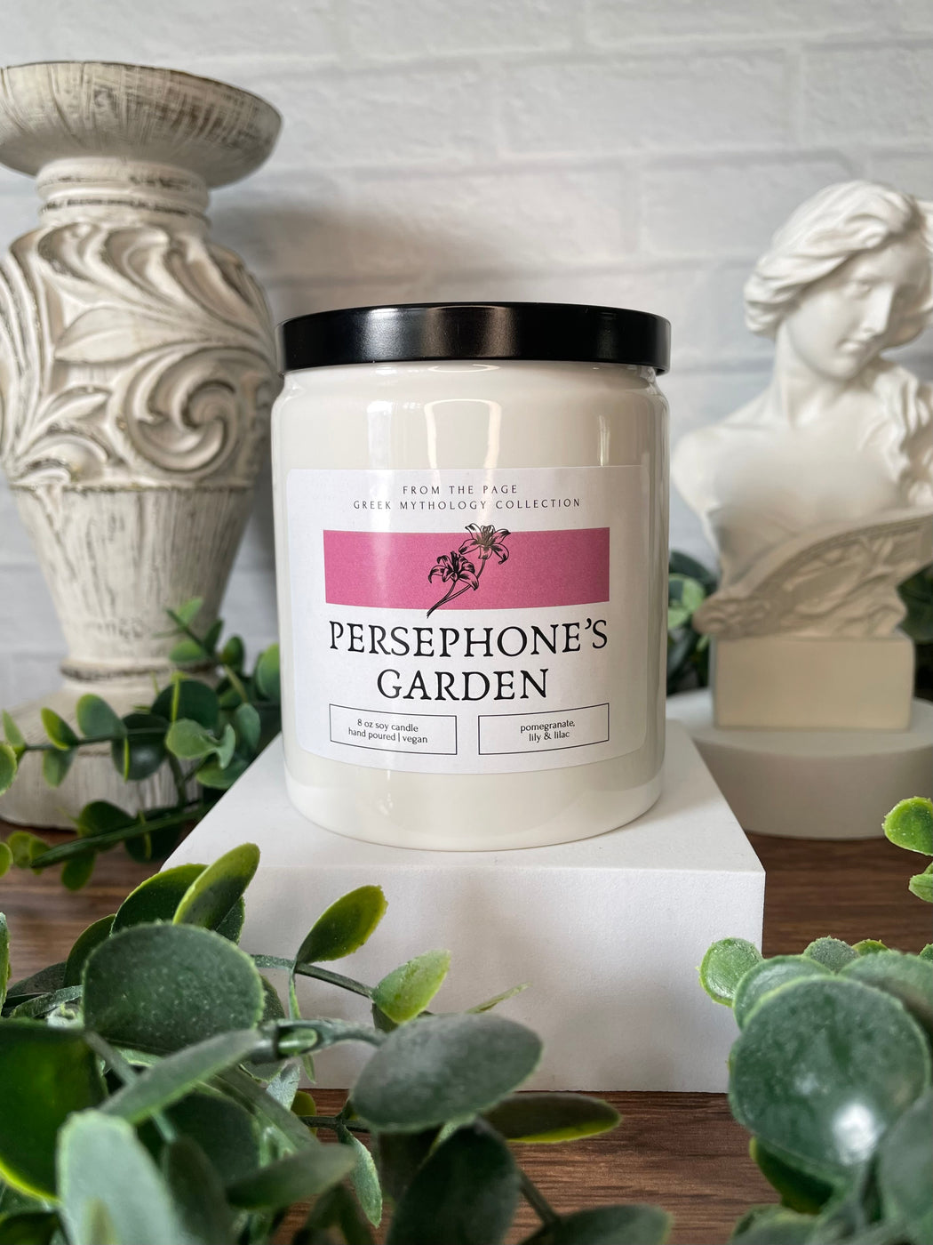 white candle with label "Persephone's Garden" and green leaves in background